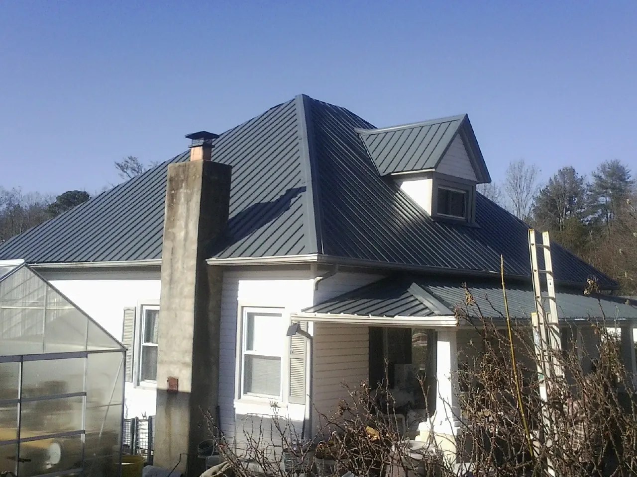 Dark blue standing seam metal roof on a white farmhouse with dormer — Slate & Tile Roof Repair by Roofing Brothers in Agency