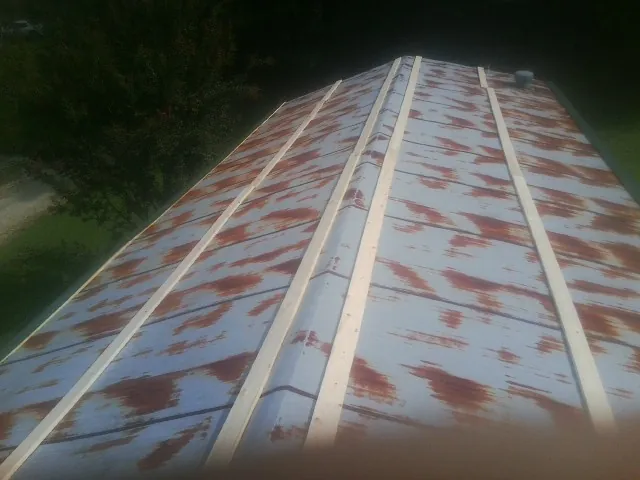 Rusted metal roof panels with new wood purlins before replacement — Storm Damage Roof Repair in Agency by Roofing Brothers