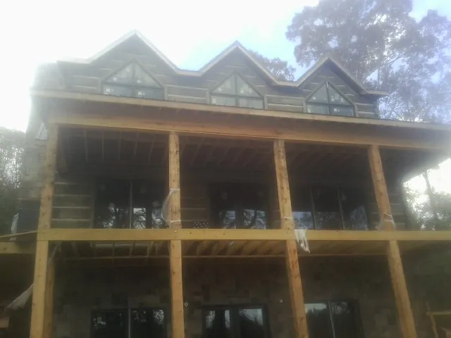 Dormers and porch framing on a large log home under construction — Roof Coating work by our crew in Agency