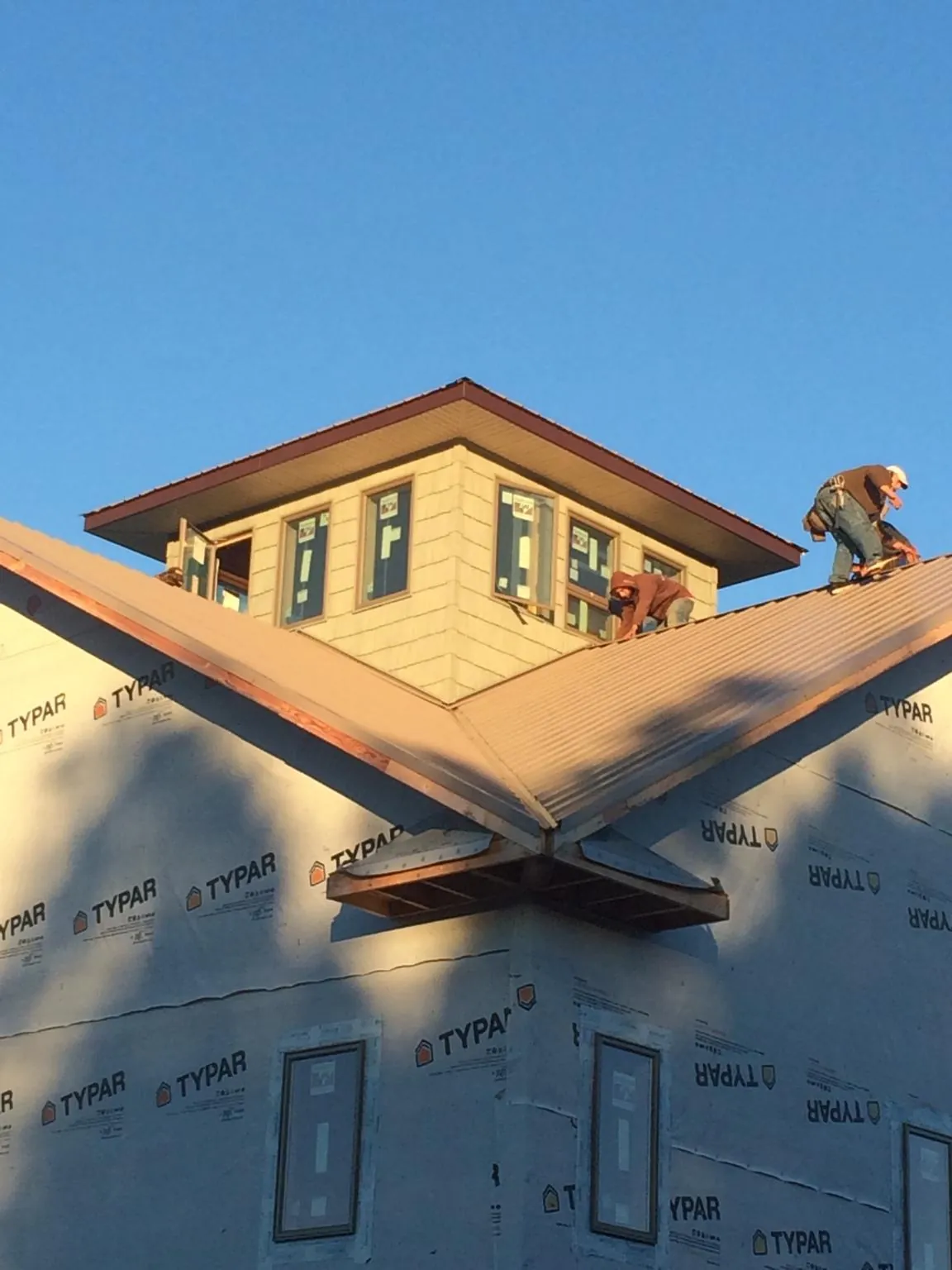 Roofers working around a rooftop cupola on a new metal roof at sunset — Roof Waterproofing in Agency by Roofing Brothers
